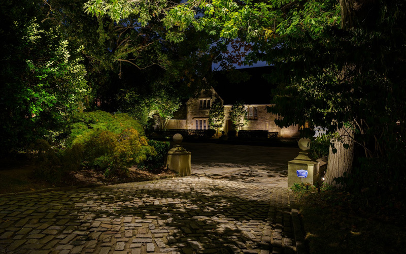 Subtle and strategic luxury outdoor lighting accentuates the architectural details and landscaping of a modern home at night.