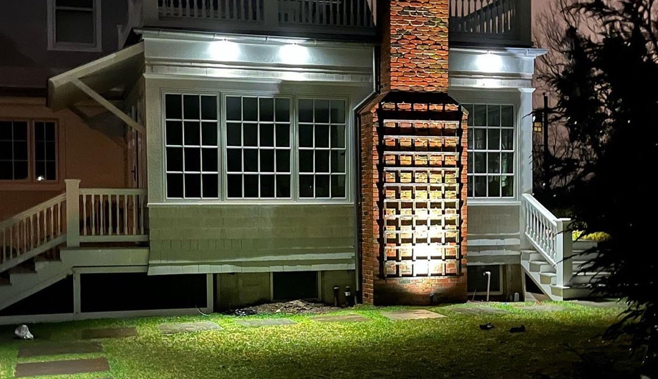 Detailed view of downlighting installation highlighting the chimney and patio area for balanced nighttime visibility.