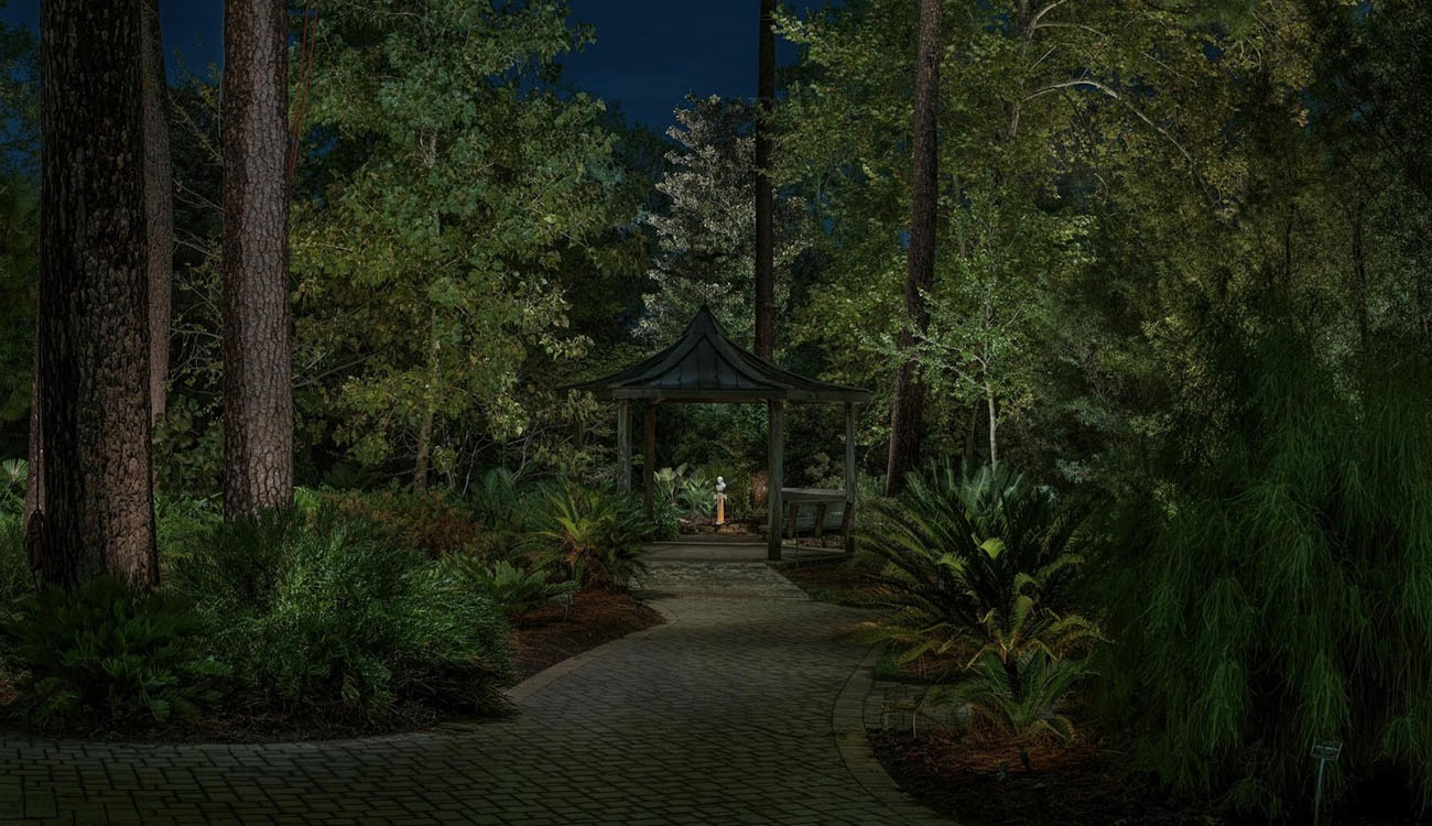 Elegant garden lighting ideas with pathway lights leading to a gazebo surrounded by lush greenery, creating a tranquil nighttime setting.