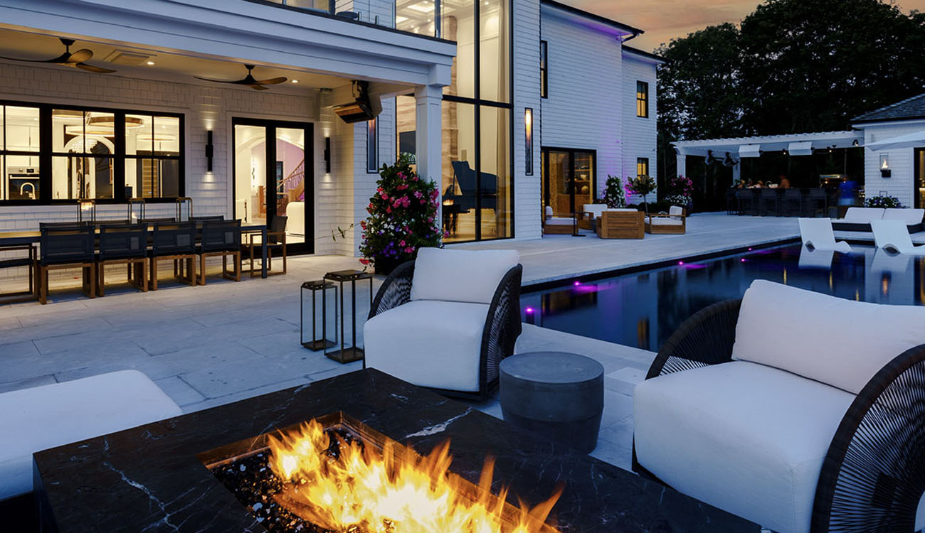 Outdoor living space with pool, fire feature, and ambient architectural lighting in Norfolk County creating a refined atmosphere.