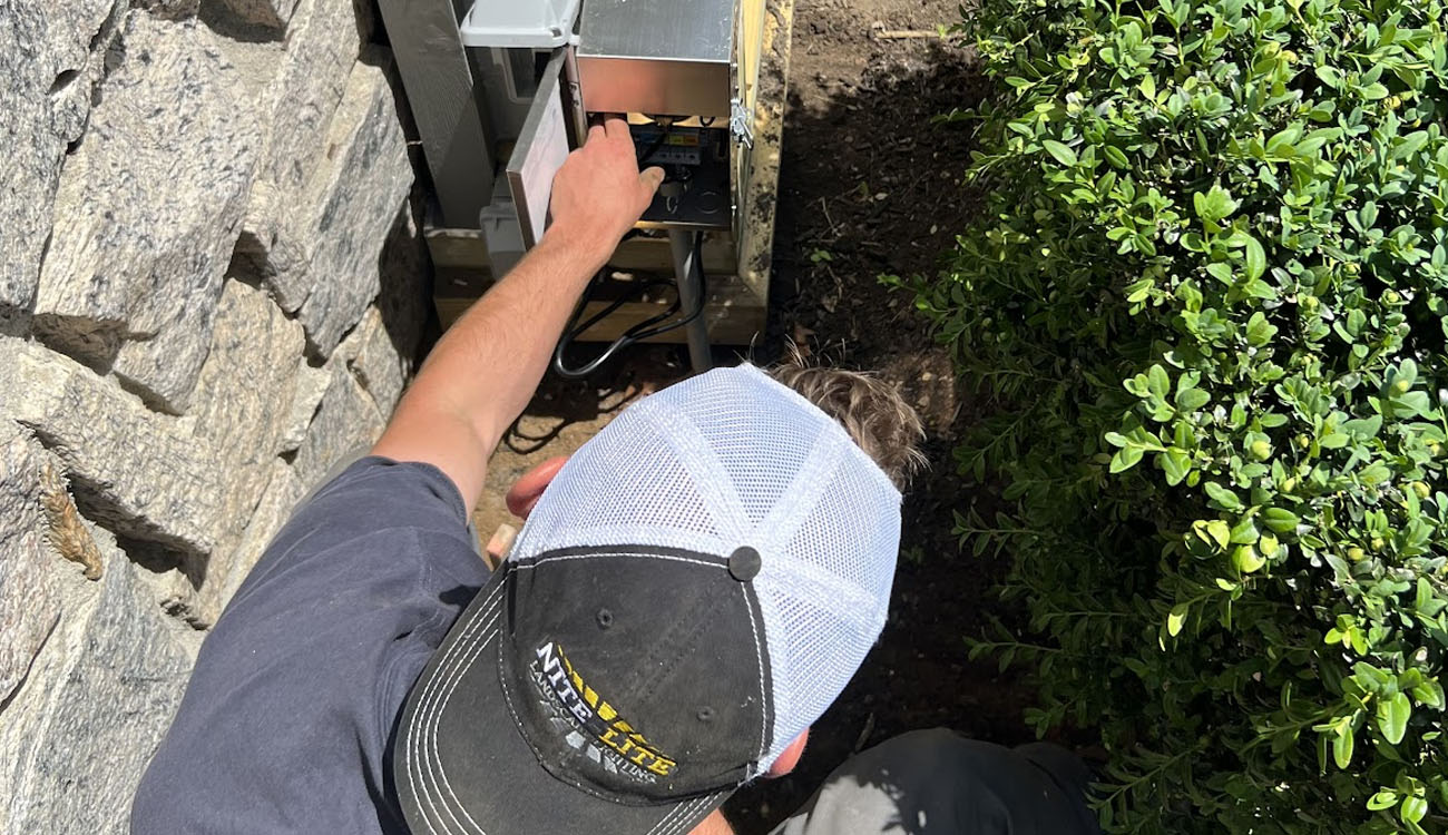 Troubleshooting Guide: Lighting Fixture Repair and Replacement in Mill Neck, NY 4 Lighting fixture repair and replacement technician adjusting components inside an outdoor lighting transformer box.