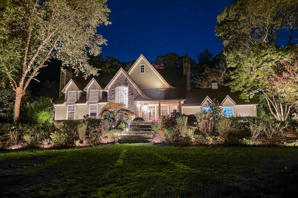 Top 10 Outdoor Lighting Maintenance Tips for Norfolk County Homeowners 4 A large home glows with warm landscape lights across the yard, showing how outdoor-lighting-maintenance keeps every fixture bright and consistent.